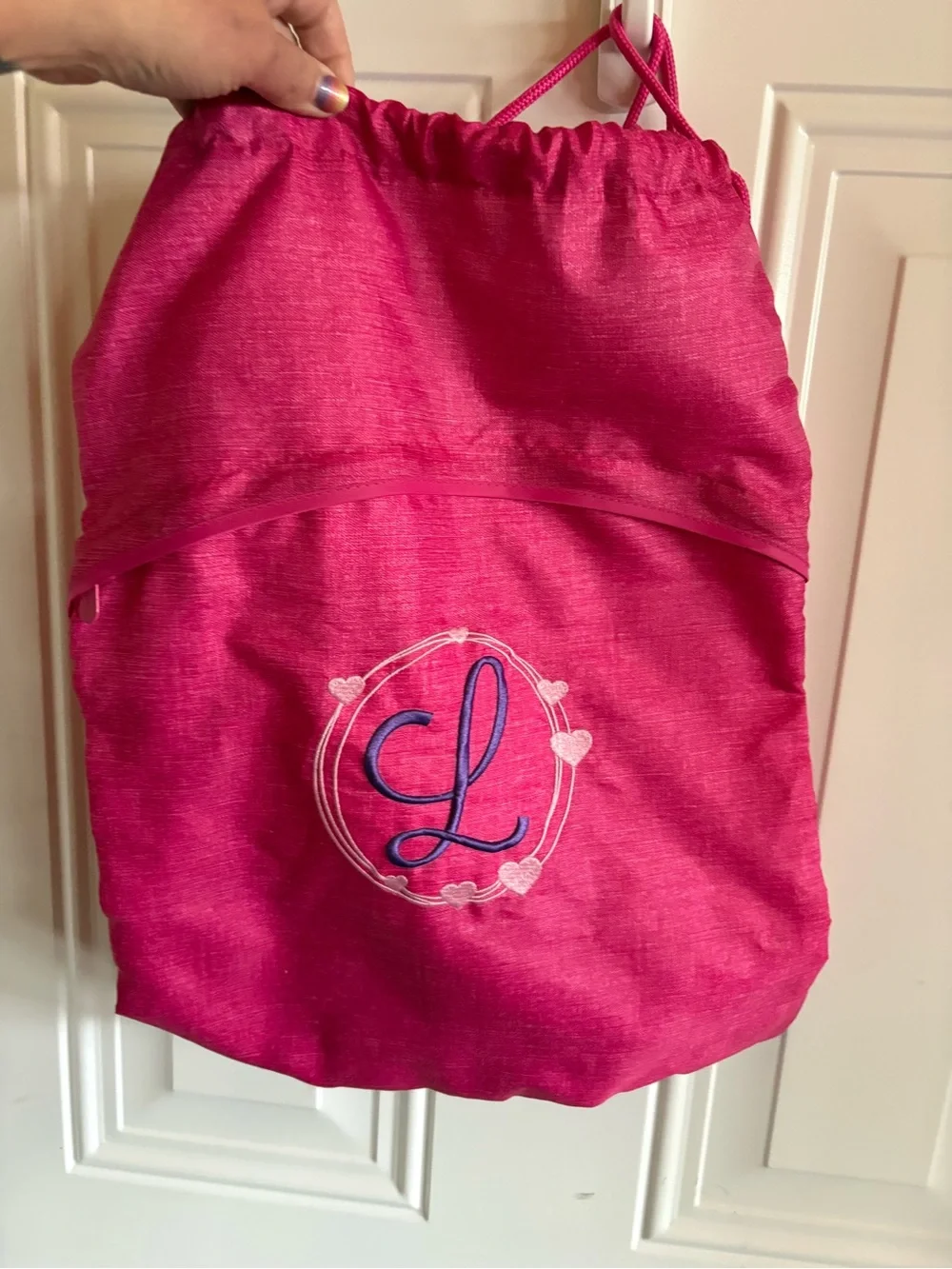 Cute personalized drawstring backpack in a vibrant pink fabric, letter L
